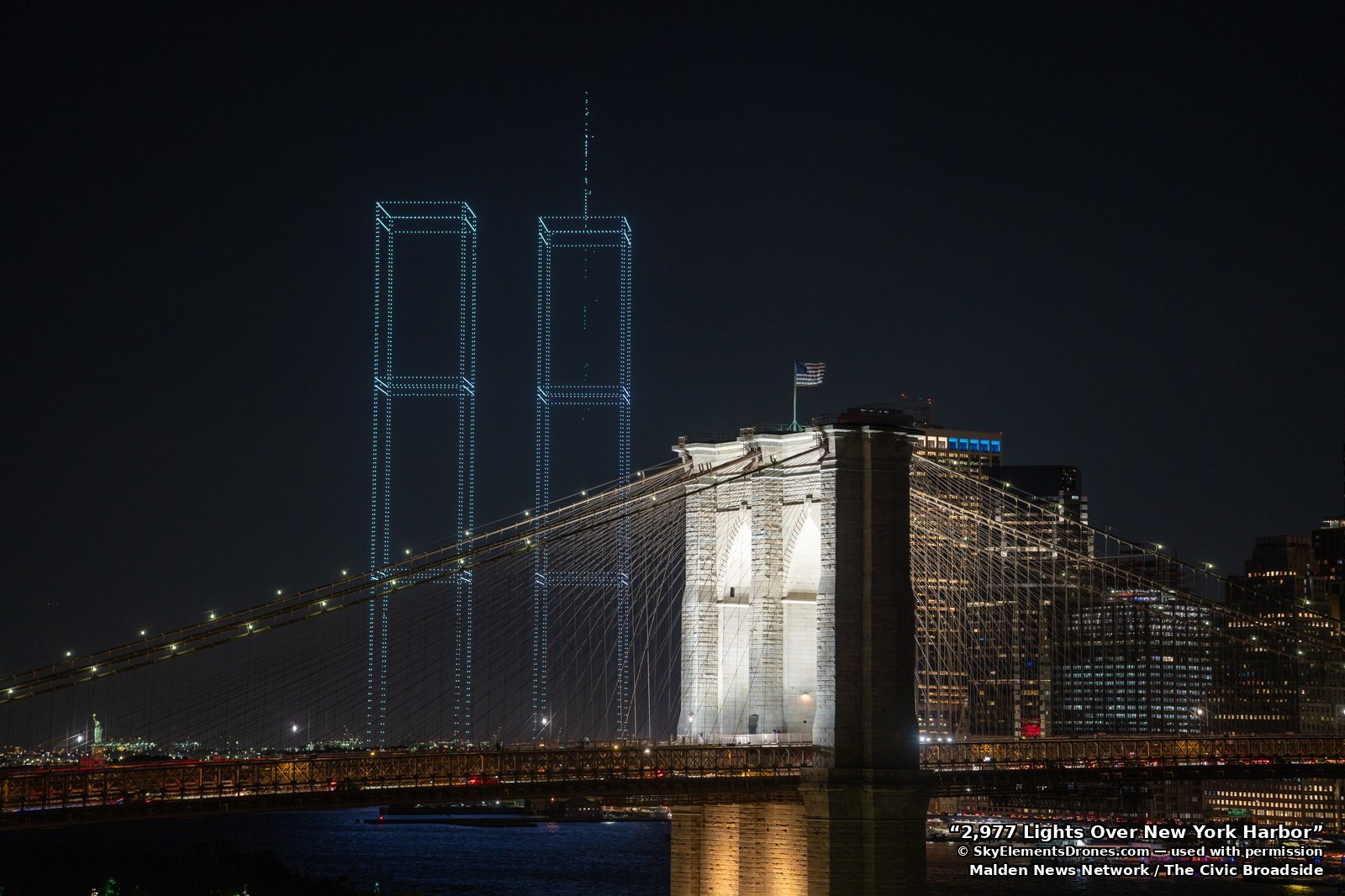 The reconstructed towers seen past the Brooklyn Bridge, with an American flag in the foreground