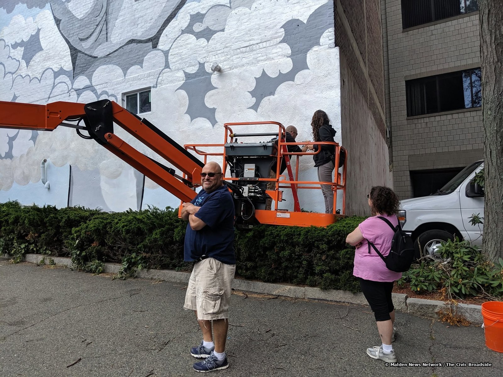 The artists on a lift, signing the mural